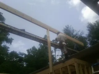 Carpenter setting a ridge beam over a new addition frame — Ice Dam Removal by Roofing Brothers in Olga