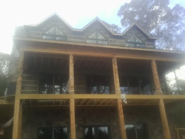 Dormers and porch framing on a large log home under construction — Roof Coating work by our crew in Olga