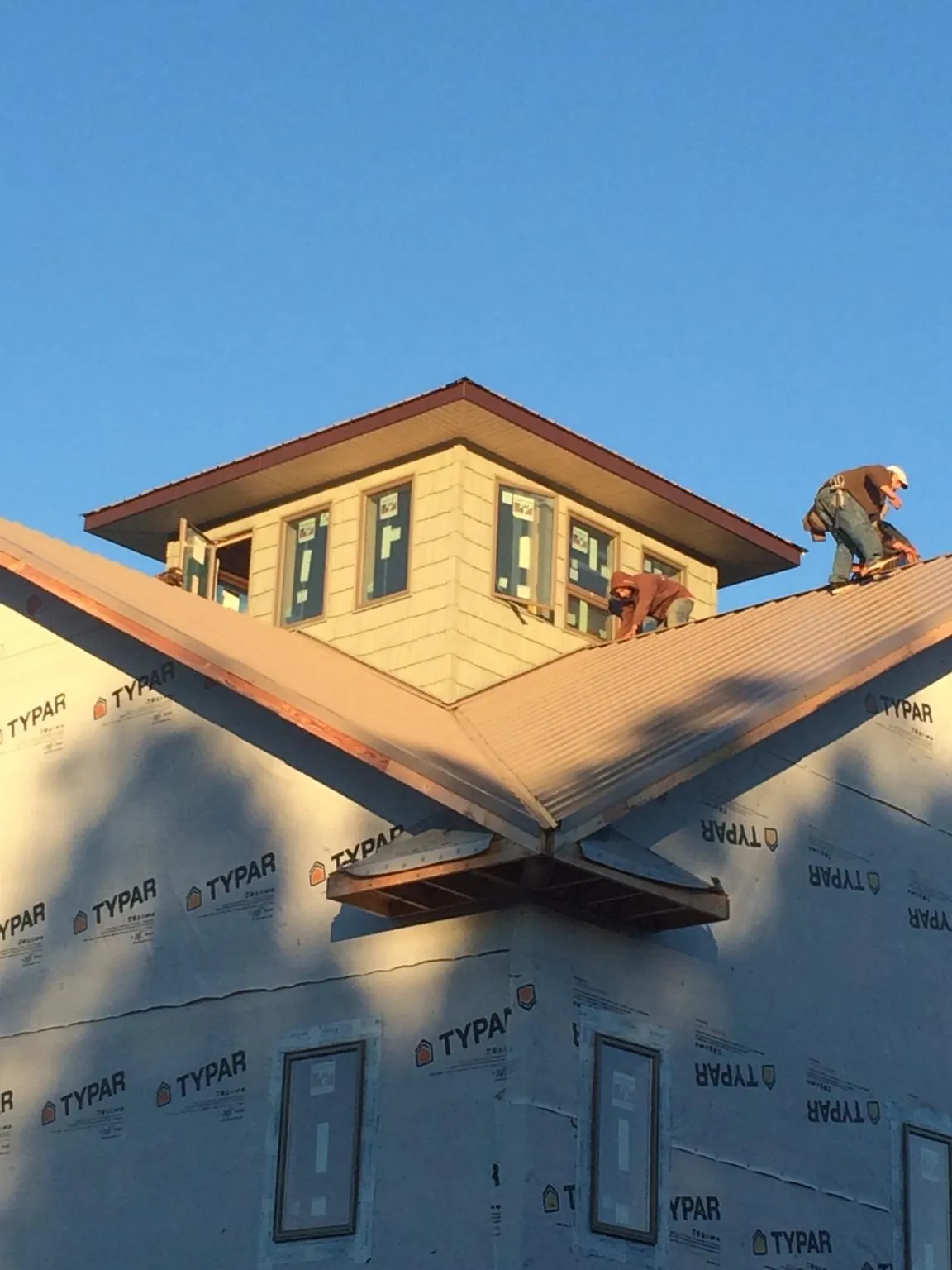 Roofers working around a rooftop cupola on a new metal roof at sunset — Roof Waterproofing in Olga by Roofing Brothers